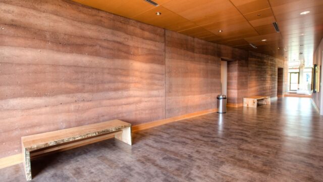Load-bearing structural insulated rammed earth wall by SIREWALL, demonstrating geological stratification and high compressive strength.