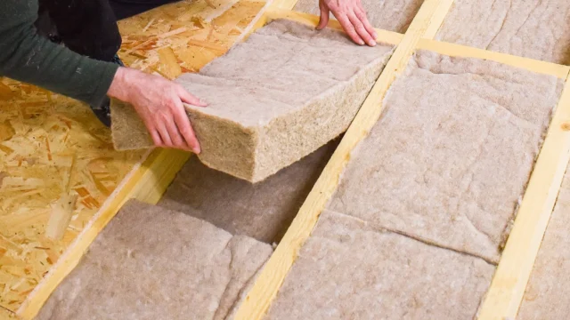 Installer placing a flexible IndiTherm hemp insulation batt (friction fit) between timber structural framing.