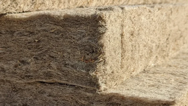 Installer placing a flexible IndiTherm hemp insulation batt (friction fit) between timber structural framing.