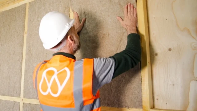 Installer placing a flexible IndiTherm hemp insulation batt (friction fit) between timber structural framing.