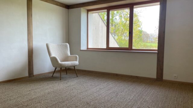 Interior wall installation using Claytec raw clay boards (Lehmbauplatten) and finished with natural clay plaster, replacing conventional gypsum drywall.