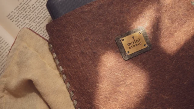 Flexible sheets of Malai bio-composite, created from coconut water-derived bacterial cellulose and natural fibers, showcasing an organic, leather-like texture.